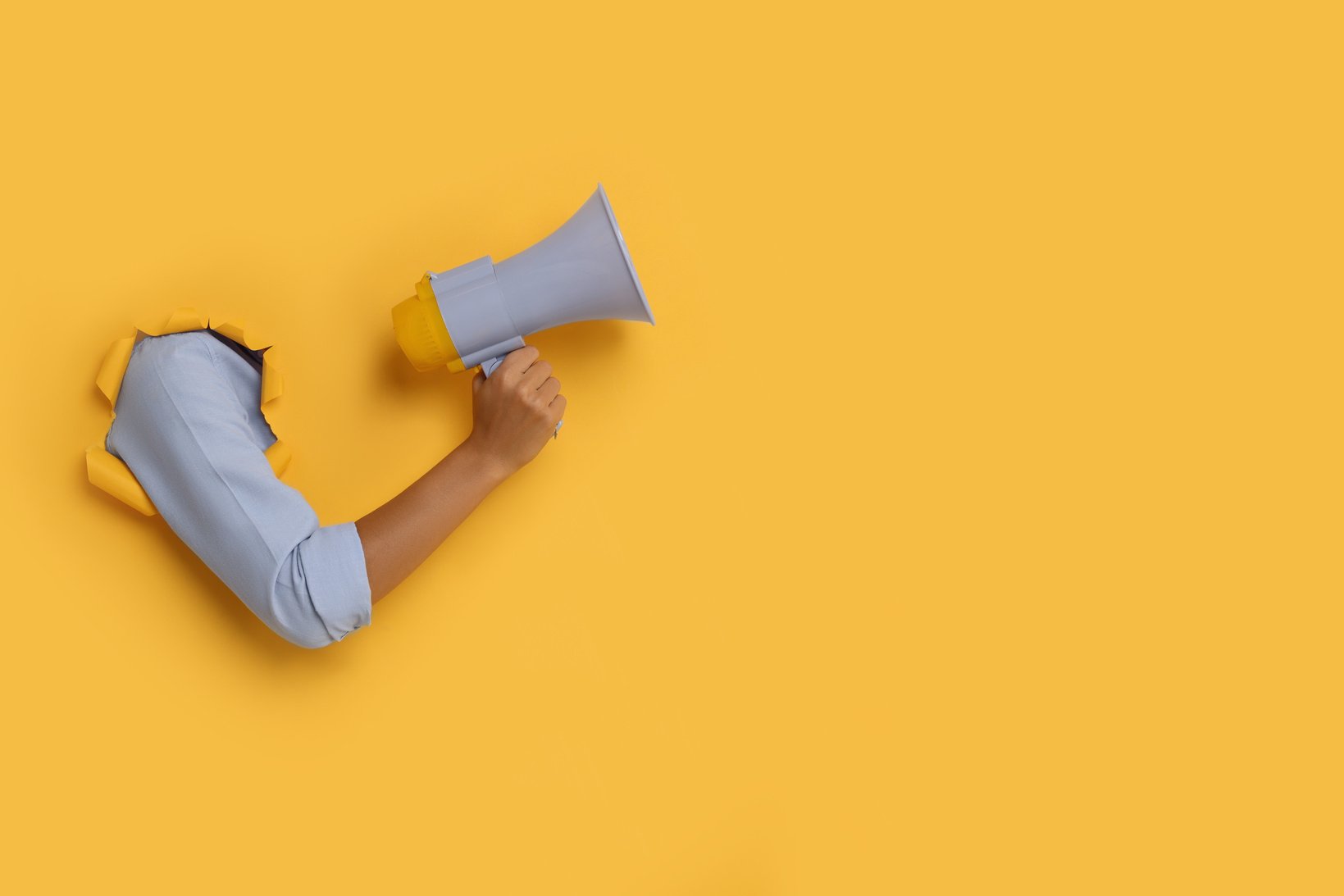 Special Promotion. Woman Holding Megaphone through Hole in Orang